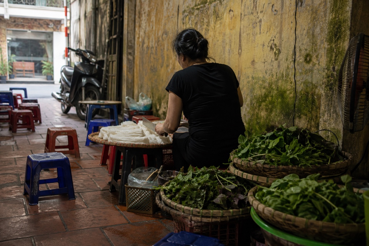 Quán bún đậu trong ngõ nhỏ Hà Nội, người bán ngồi xắt bún lá bên mấy cái mẹt tre, ghế nhựa thấp kê sát tường vàng rêu